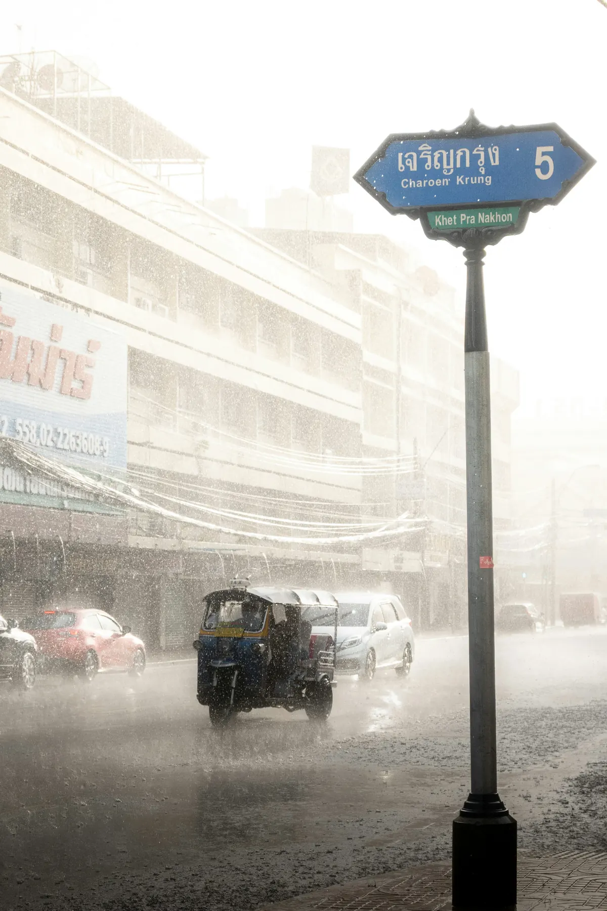 รถตุ๊กตุ๊กเคลื่อนผ่านถนนกรุงเทพฯ ขณะฝนตกหนัก